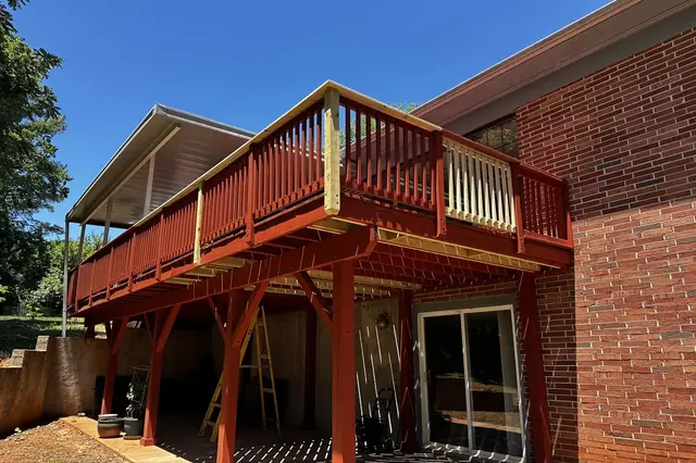 Elevated second-story deck with red-stained railing on a brick home