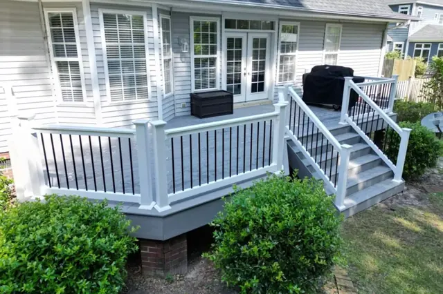 Gray composite deck with white railing, stairs and an outdoor grill area