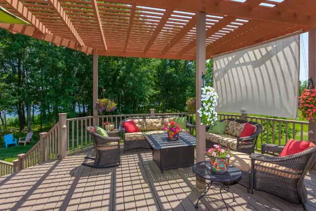 Wood deck with a stained pergola, outdoor sofa and wooded view